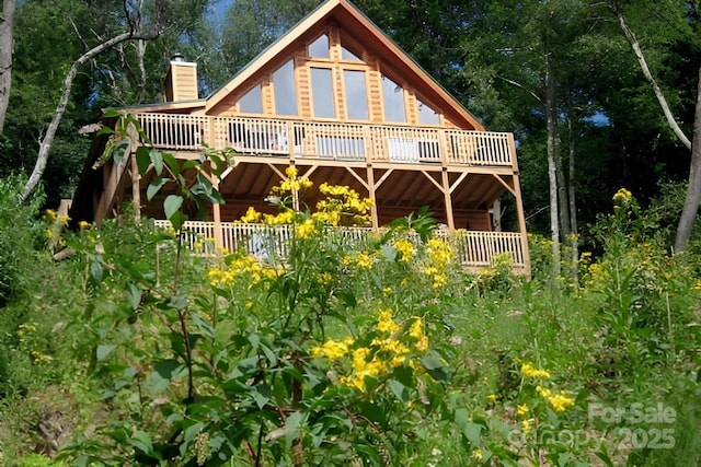 rear view of house featuring a chimney and a deck
