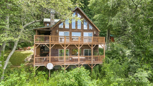 rear view of property featuring a view of trees and a deck