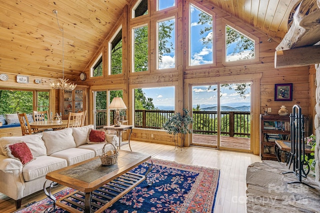 living room with wooden walls, wood ceiling, a wealth of natural light, and high vaulted ceiling