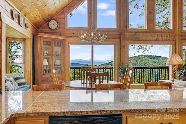 kitchen with wooden ceiling, wood walls, a mountain view, and a wealth of natural light