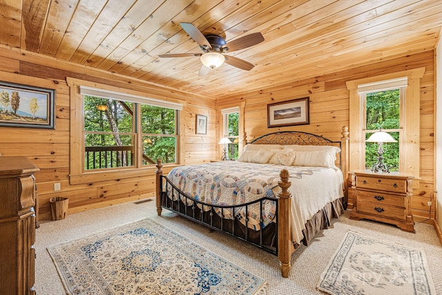 carpeted bedroom with wood ceiling, ceiling fan, wood walls, and visible vents