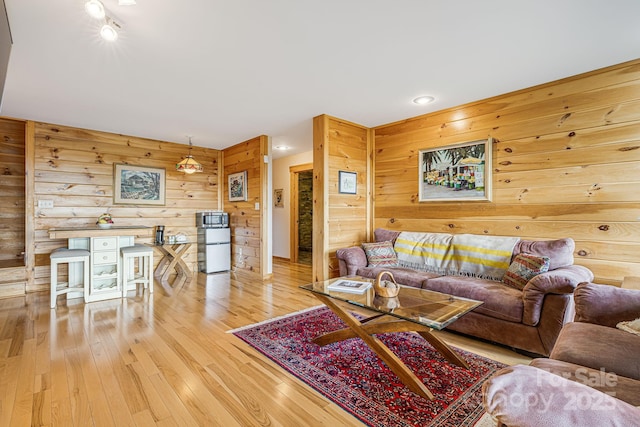 living area with light wood-type flooring, recessed lighting, and wooden walls