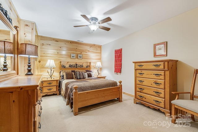 bedroom featuring visible vents, a ceiling fan, wooden walls, and light carpet