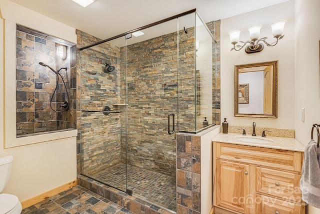 bathroom with vanity, toilet, baseboards, stone finish flooring, and a shower stall