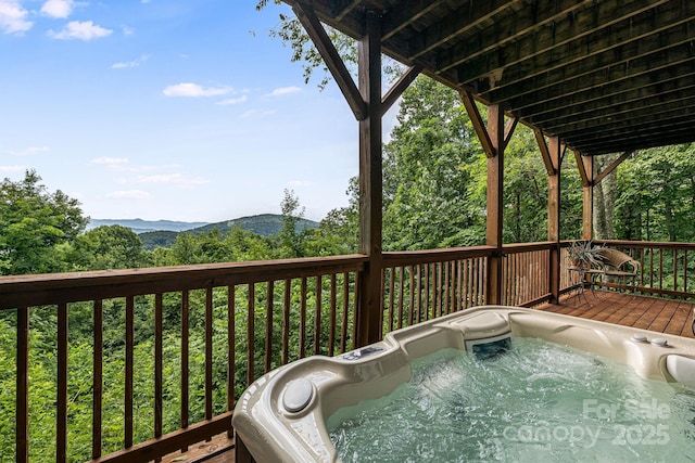 deck with a mountain view and a hot tub