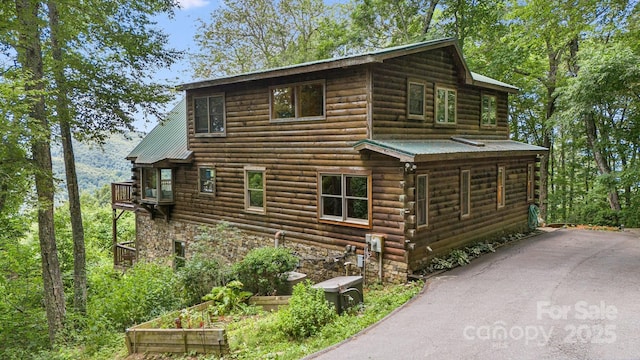 view of side of home with log siding, metal roof, and stone siding