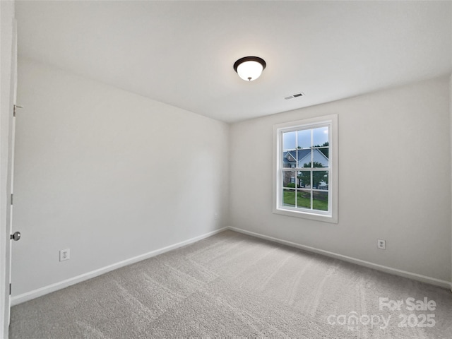 carpeted spare room featuring baseboards and visible vents