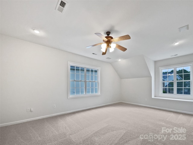 additional living space with baseboards, a wealth of natural light, a ceiling fan, and light colored carpet