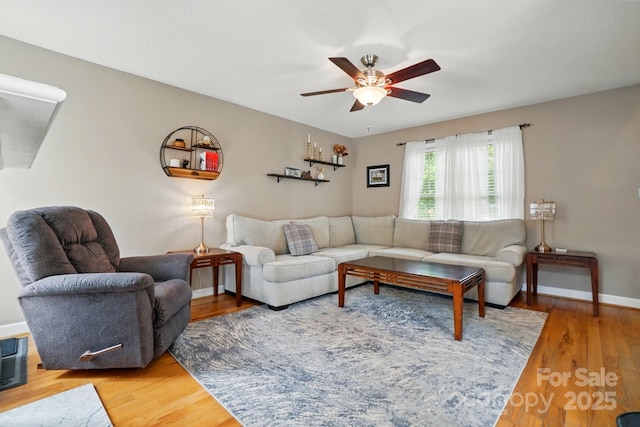 living room featuring baseboards, ceiling fan, and wood finished floors