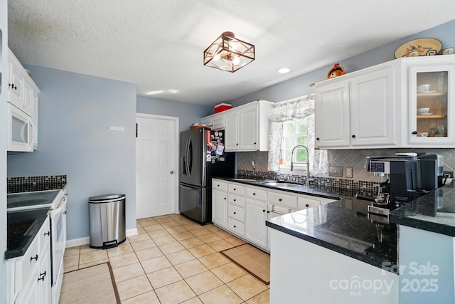 kitchen featuring white cabinets, a sink, white appliances, light tile patterned floors, and tasteful backsplash