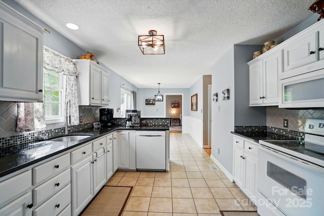kitchen featuring a sink, a healthy amount of sunlight, white appliances, and a chandelier