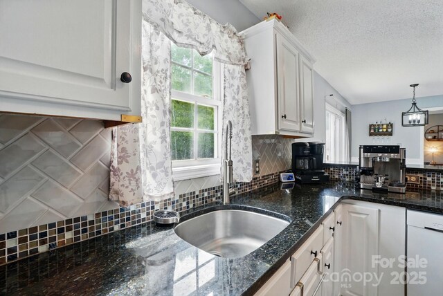 kitchen featuring a healthy amount of sunlight, white cabinets, backsplash, and a sink