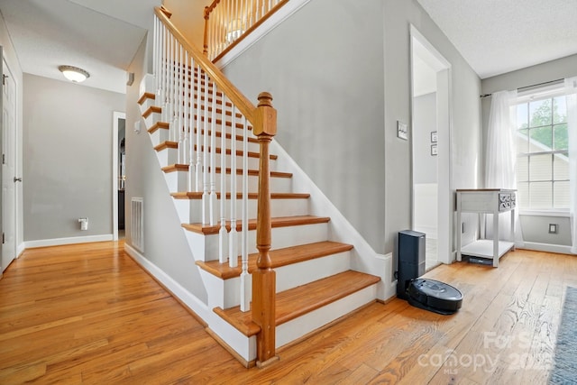 stairs with baseboards, visible vents, and hardwood / wood-style floors