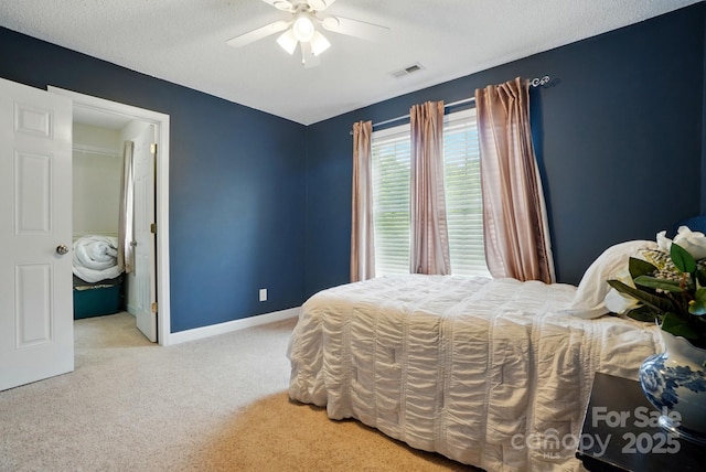 carpeted bedroom featuring a ceiling fan, baseboards, visible vents, and a textured ceiling