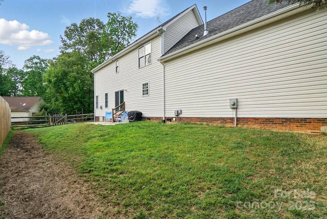 back of property featuring fence, a yard, and crawl space