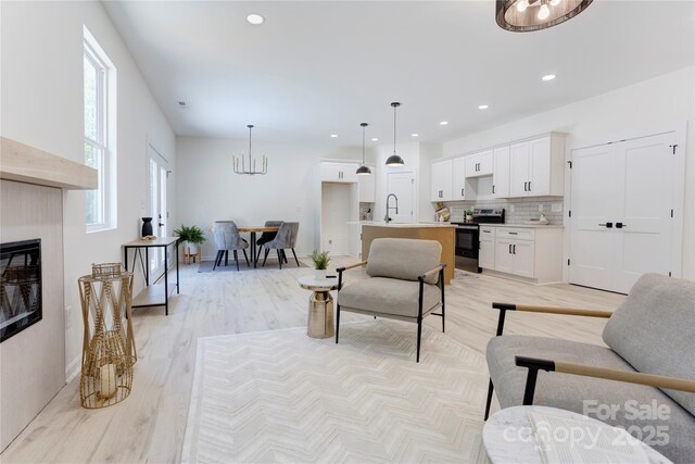 3300 Travis Ln NW, Concord, NC 28027 - living room with a glass covered fireplace, recessed lighting, light wood-style flooring, and a notable chandelier