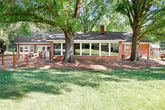 back of property featuring brick siding, fence, and a yard