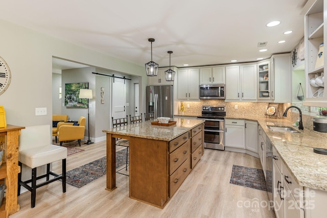 4329 Island Ford Rd, Brevard, NC 28712 - kitchen featuring appliances with stainless steel finishes, a sink, light wood-type flooring, a barn door, and tasteful backsplash