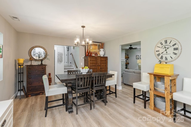 4329 Island Ford Rd, Brevard, NC 28712 - dining space featuring light wood-style floors, a chandelier, ceiling fan, and stairway