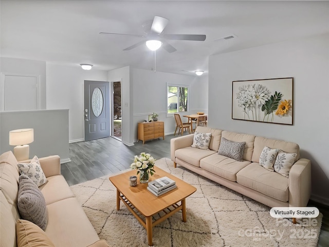living area with baseboards, a ceiling fan, wood finished floors, and visible vents