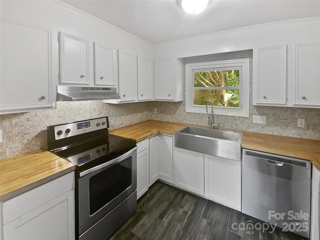 kitchen with white cabinetry, under cabinet range hood, a sink, wood counters, and appliances with stainless steel finishes