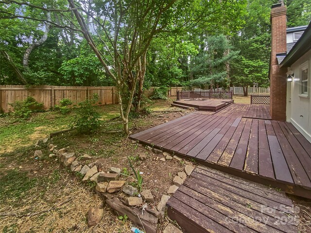 wooden terrace with a fenced backyard