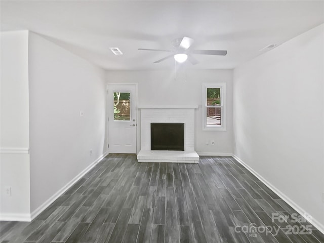 unfurnished living room with baseboards, a ceiling fan, a brick fireplace, and wood finished floors