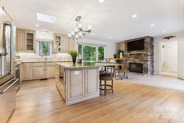 115 Forestcliff Ct NE, Concord, NC 28025 - kitchen with a skylight, a breakfast bar area, stainless steel appliances, a center island, and light wood-type flooring