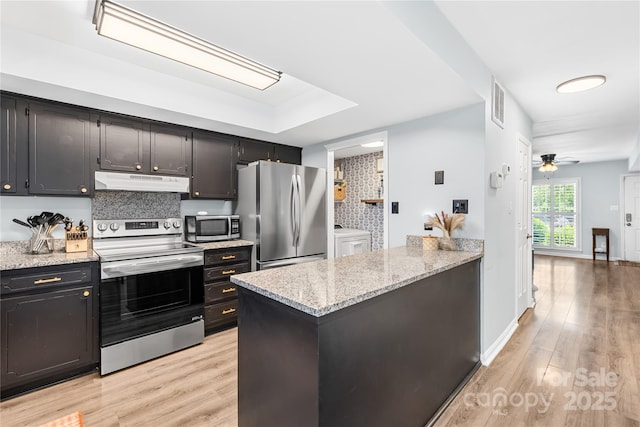 9214 N Vicksburg Park Ct, Charlotte, NC 28210 - kitchen with light wood-style floors, appliances with stainless steel finishes, under cabinet range hood, and washer and dryer