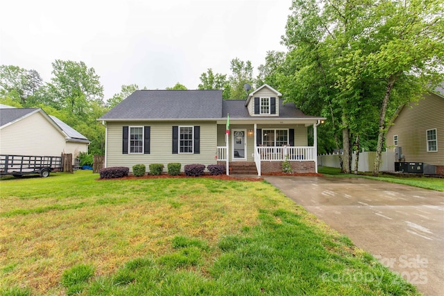 new england style home featuring a porch, roof with shingles, central air condition unit, and a front yard