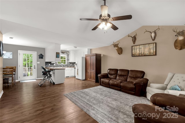 living room with vaulted ceiling, a ceiling fan, and dark wood finished floors