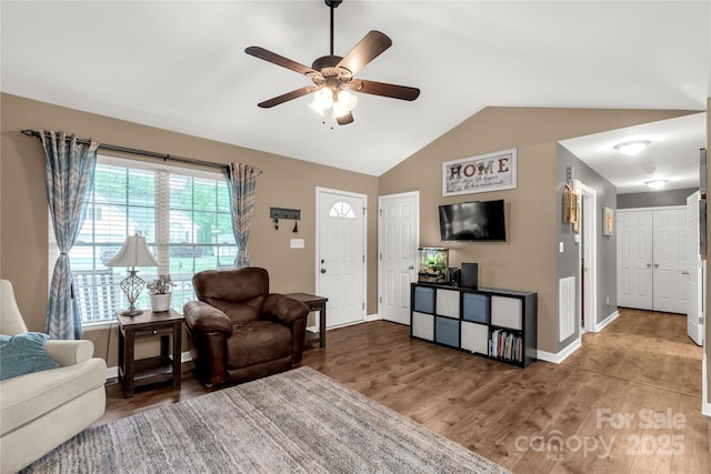 living area with baseboards, a ceiling fan, wood finished floors, and lofted ceiling