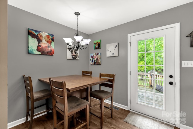 dining room with baseboards, wood finished floors, visible vents, and an inviting chandelier