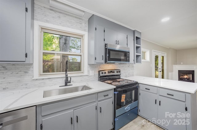 kitchen with a sink, appliances with stainless steel finishes, backsplash, and a peninsula
