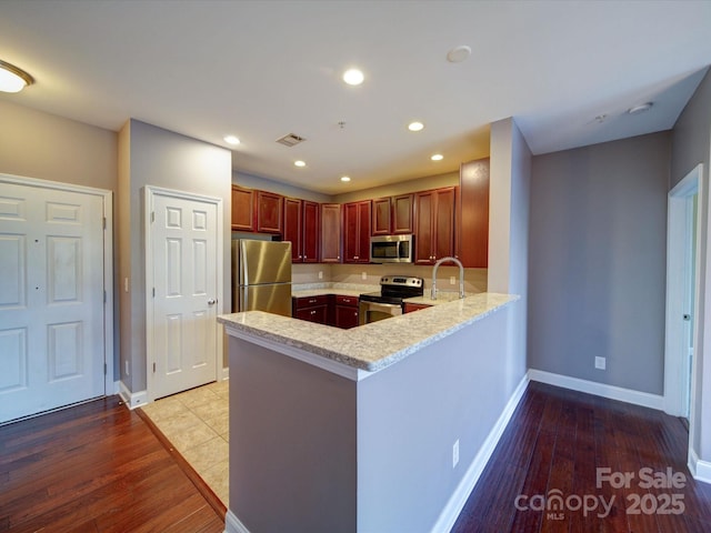 1000 E Woodlawn Rd Unit 402, Charlotte, NC 28209 - kitchen featuring light stone countertops, light wood finished floors, stainless steel appliances, baseboards, and a peninsula