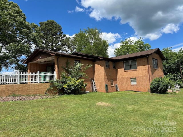view of front of house with brick siding, fence, and a front yard
