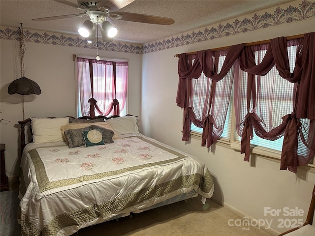 carpeted bedroom with ceiling fan, a textured ceiling, and baseboards