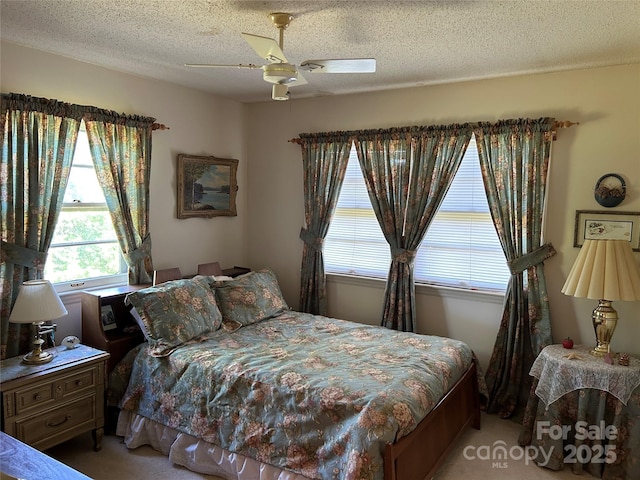 bedroom with light colored carpet, multiple windows, a textured ceiling, and a ceiling fan