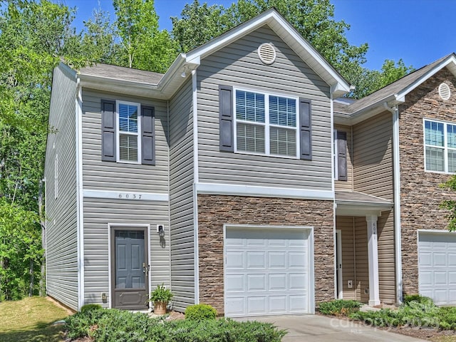 view of front of house featuring an attached garage, driveway, and stone siding