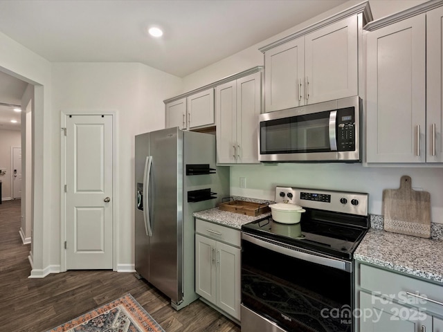 kitchen with light stone countertops, appliances with stainless steel finishes, gray cabinets, and dark wood-type flooring