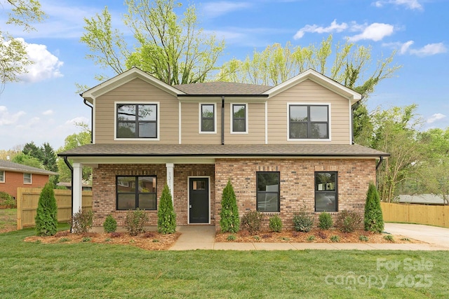 craftsman-style house with brick siding, fence, covered porch, and a front yard