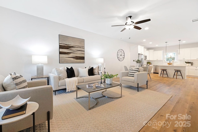 living area featuring light wood-style floors, ceiling fan, recessed lighting, and visible vents