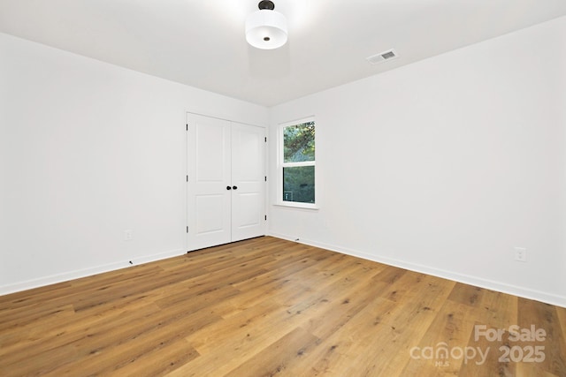 unfurnished room with visible vents, light wood-style floors, and baseboards
