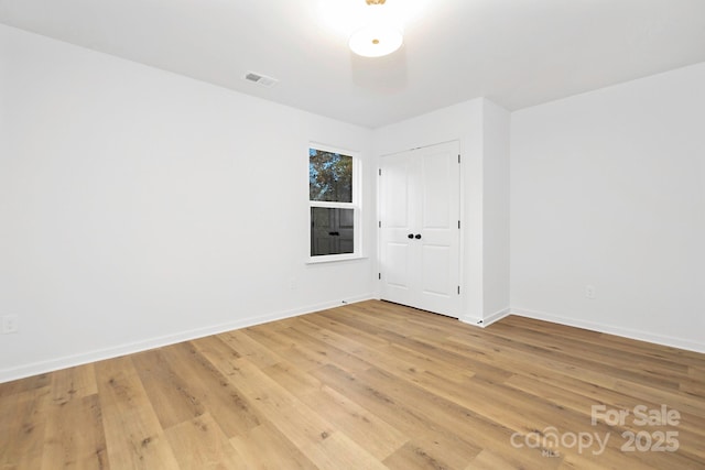 empty room with baseboards, visible vents, and light wood-type flooring
