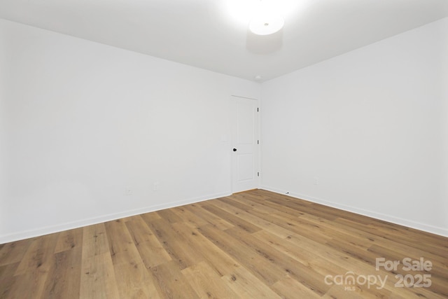 spare room with baseboards and wood finished floors