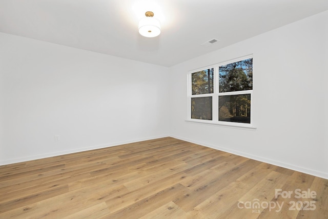 unfurnished room featuring baseboards, wood finished floors, and visible vents