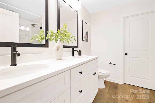 bathroom featuring a sink, a shower stall, toilet, and wood finished floors