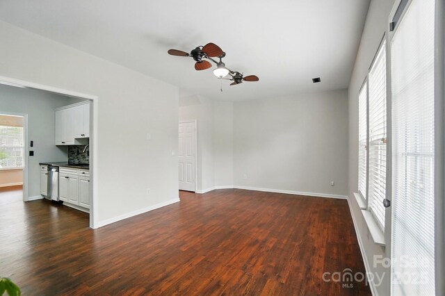 empty room with ceiling fan, baseboards, and dark wood-type flooring