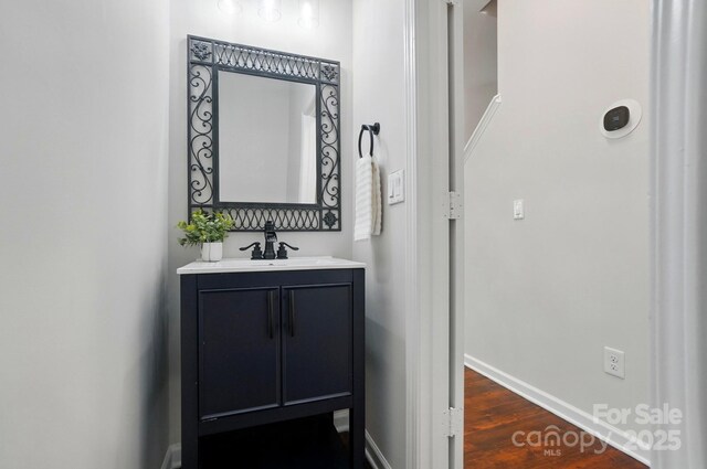 hall with baseboards, dark wood finished floors, and a sink