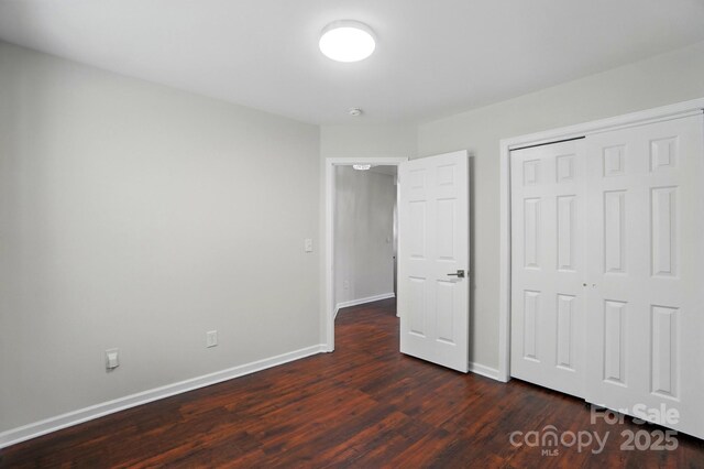 unfurnished bedroom with baseboards, a closet, and dark wood-style floors